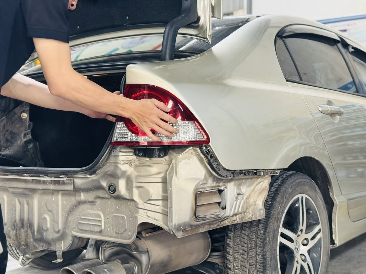 Kỹ thuật viên kiểm tra cản sau trước khi đồng sơn ô tô phục hồi xe va chạm