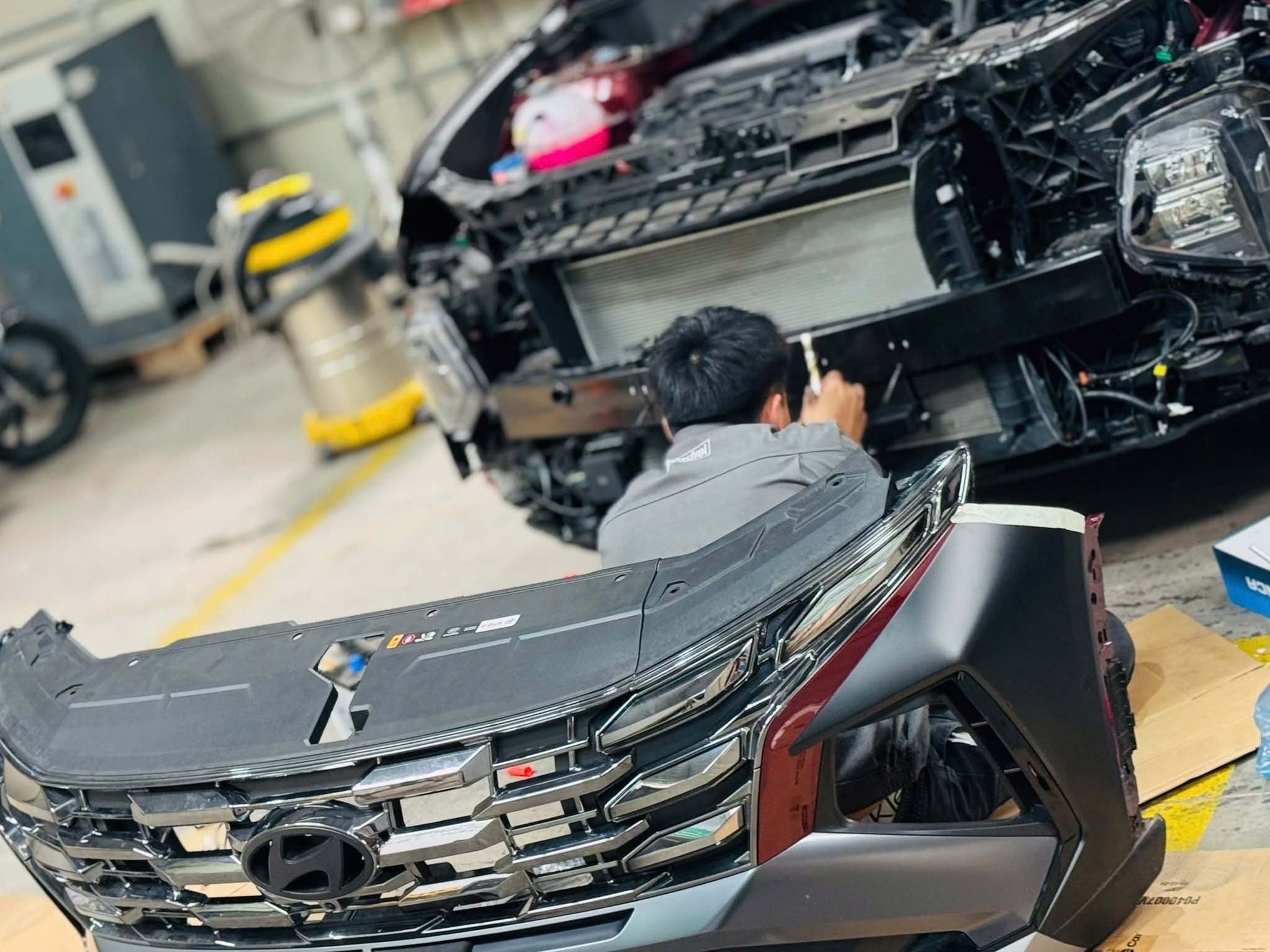Kỹ thuật viên tháo cản trước Hyundai Tucson để lắp đèn
